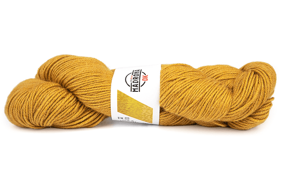 Mustard yellow skein of yarn with a label on a white background