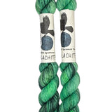 Two mini skeins of wool yarn hand dyed in Wyoming in the color green and black streaks