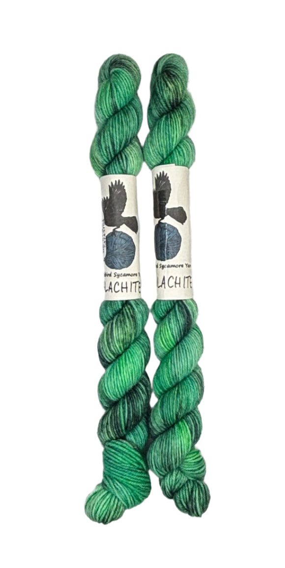 Two mini skeins of wool yarn hand dyed in Wyoming in the color green and black streaks