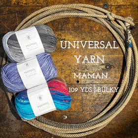 Multicolored Balls of Universal Yarn Maman Acrylic Yarn on a wooden surface