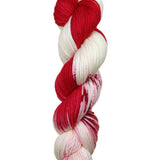 A skein of hand-dyed fingering/sock yarn color white red speckles