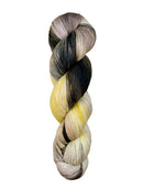 A skein of hand-dyed fingering/sock yarn color grey yellow peach mauve black