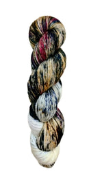 A skein of hand-dyed fingering/sock yarn color tan white blue red black speckles