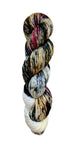 A skein of hand-dyed fingering/sock yarn color tan white blue red black speckles