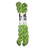 Two mini skeins of green yarn in the color green on a white background