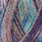Close-up image of multi-colored yarn alongside a knit up swatch in the colors tan blue purple pink
