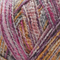 Close-up image of multi-colored yarn alongside a knit up swatch in the colors pink purple grey orange