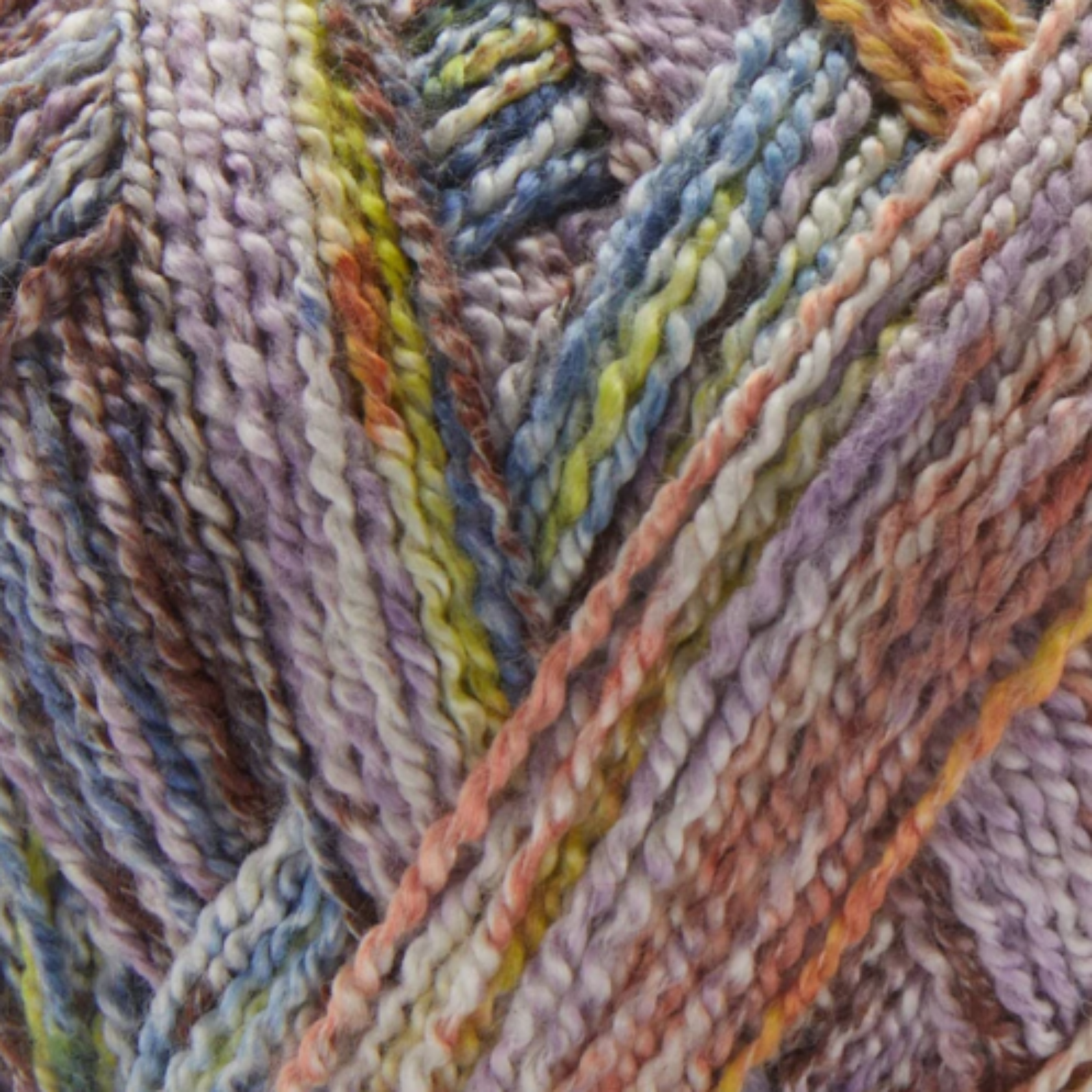 Close-up image of multi-colored yarn alongside a knit up swatch in the colors blue green brown orange yellow