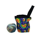 Colorful tie-dye fabric draw-string pouch with a ball of yarn on a white background