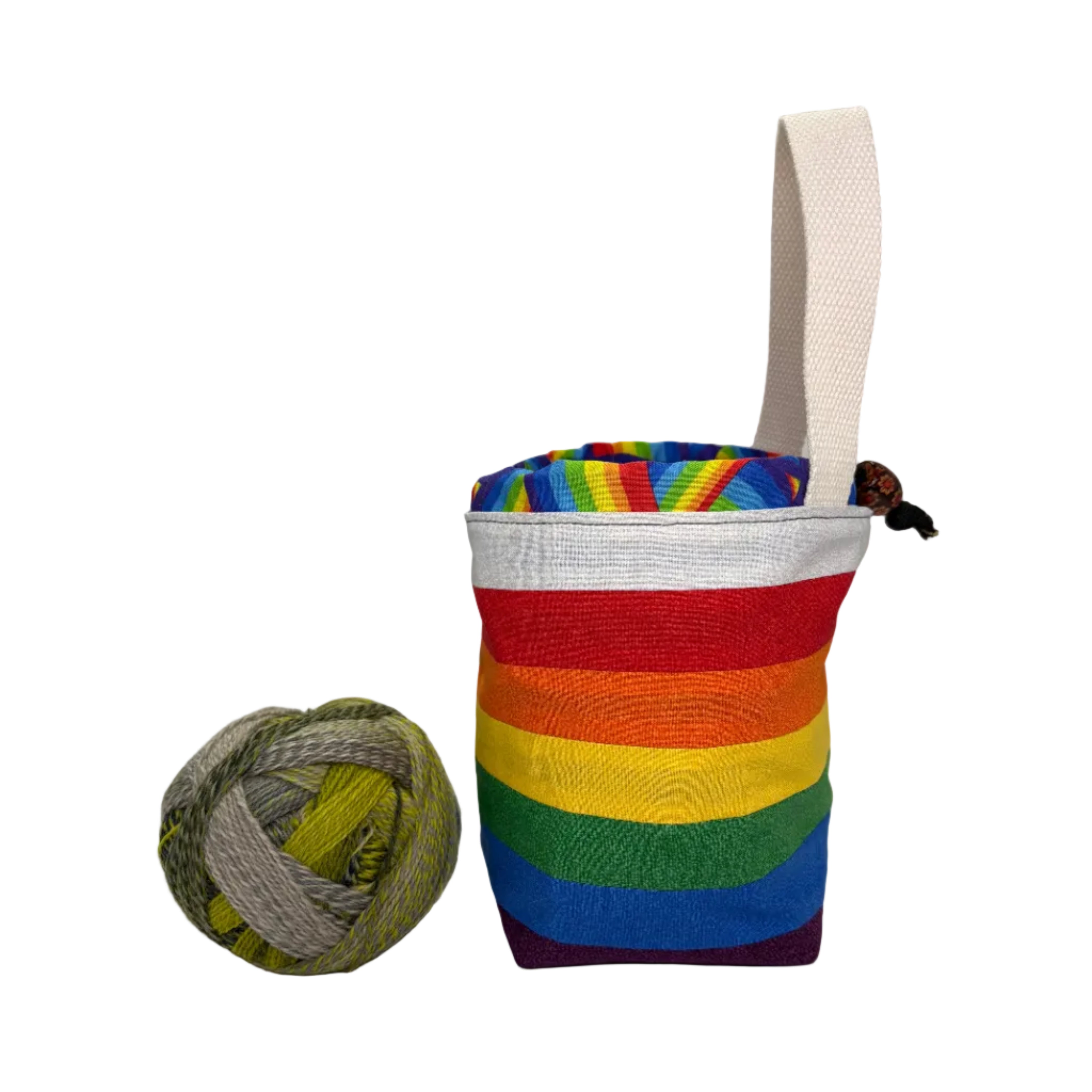 Colorful striped pouch with a handle next to a ball of yarn on a white surface.