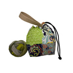 Colorful patchwork fabric pouch with a woven handle and a ball of yarn on a white surface