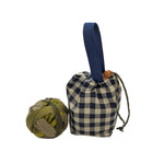 Blue and white checkered drawstring bag with a blue handle next to a ball of yarn on a white surface.