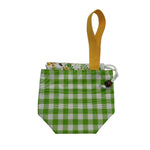 A small fabric pouch with a green and white gingham pattern, a mustard yellow webbed loop handle, and a floral patterned lining visible at the top.