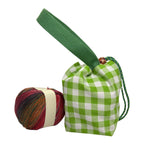 A green and white gingham drawstring pouch with a wide green handle, displayed next to a ball of variegated yarn 