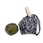 Yarn ball next to a blue and white floral patterned drawstring bag on a white background