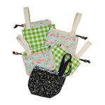 Collection of fabric bags with a drawstring and short handle in different patterns on a white background