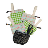 Collection of fabric bags with a drawstring and short handle in different patterns on a white background