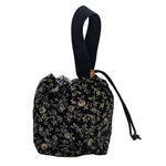 Small black floral drawstring bag with a wrist strap on a white surface.