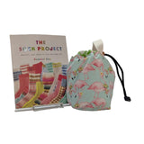 Flamingo-patterned drawstring bag with 'The Sock Project' book on a white surface