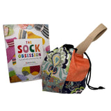 Colorful fabric bag with drawstring and a book titled 'The Sock Obsession' on a white surface.