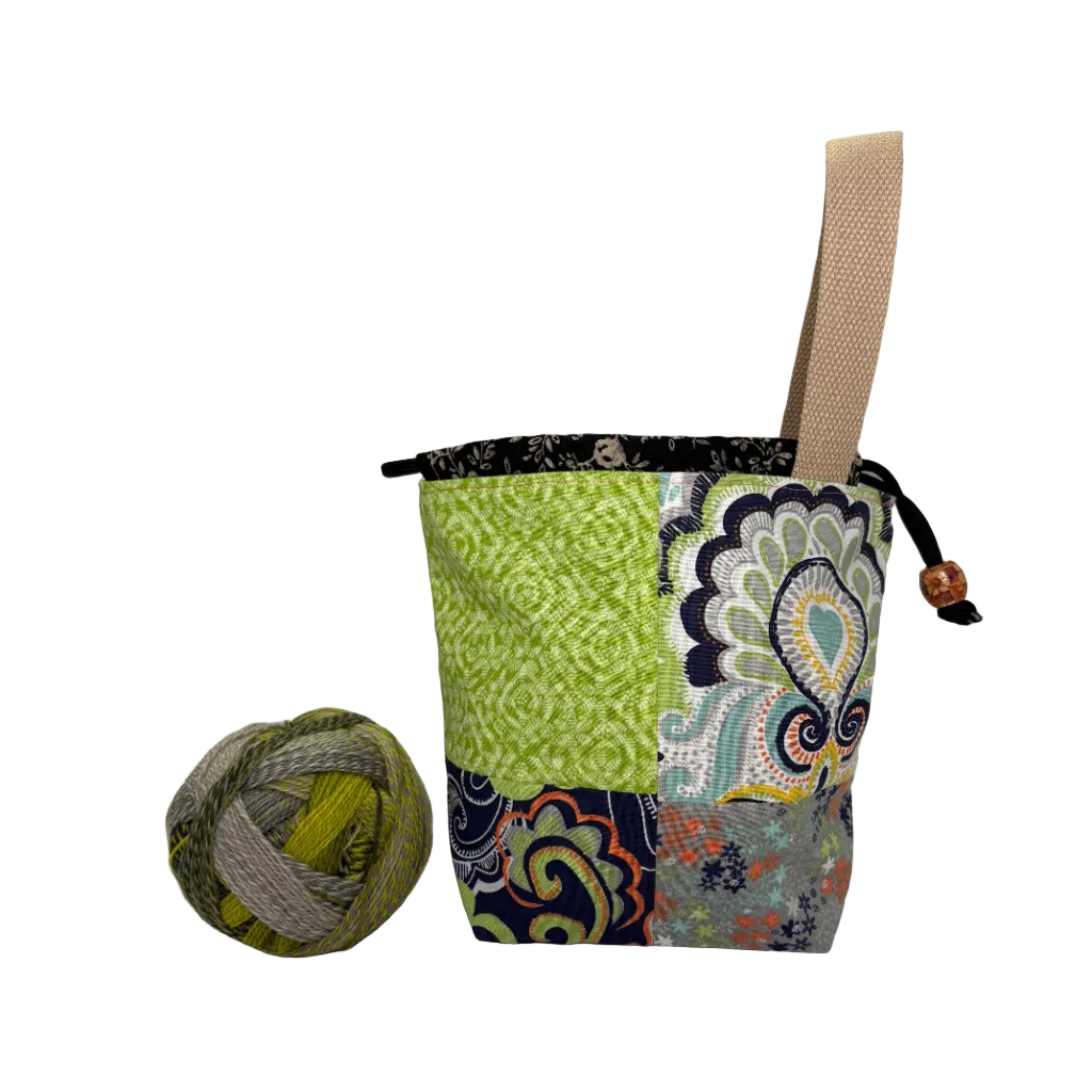 Fabric project bag with colorful patchwork pattern next to a ball of yarn on a white background