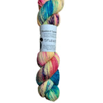 A skein of hand-dyed fingering/sock yarn color yellow pink blue purple teal speckles