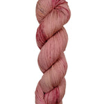 A skein of hand-dyed fingering/sock yarn color pink red brown speckles