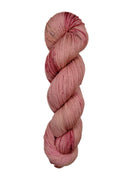 A skein of hand-dyed fingering/sock yarn color pink red brown speckles