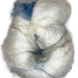 A hand-dyed wool rolag in the colors natural white blue green brown