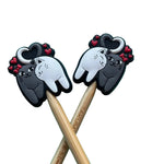 Two wooden needles with stitch stoppers shaped like cats with their ail making a heart