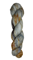 Skein of hand dyed fingering weight yarn in the color grey orange black speckles