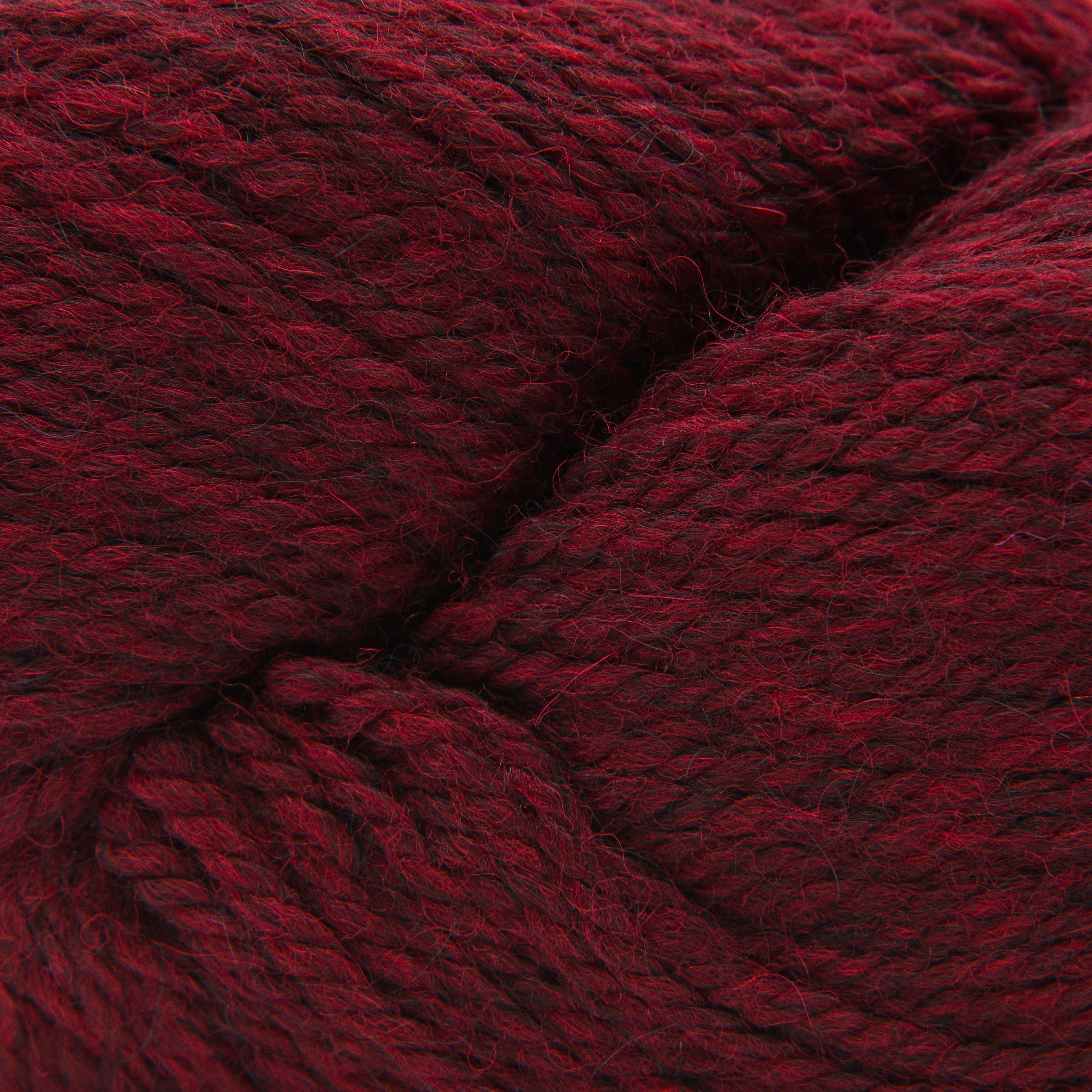 A close-up of dark red yarn with a soft, fuzzy texture, filling the entire frame.