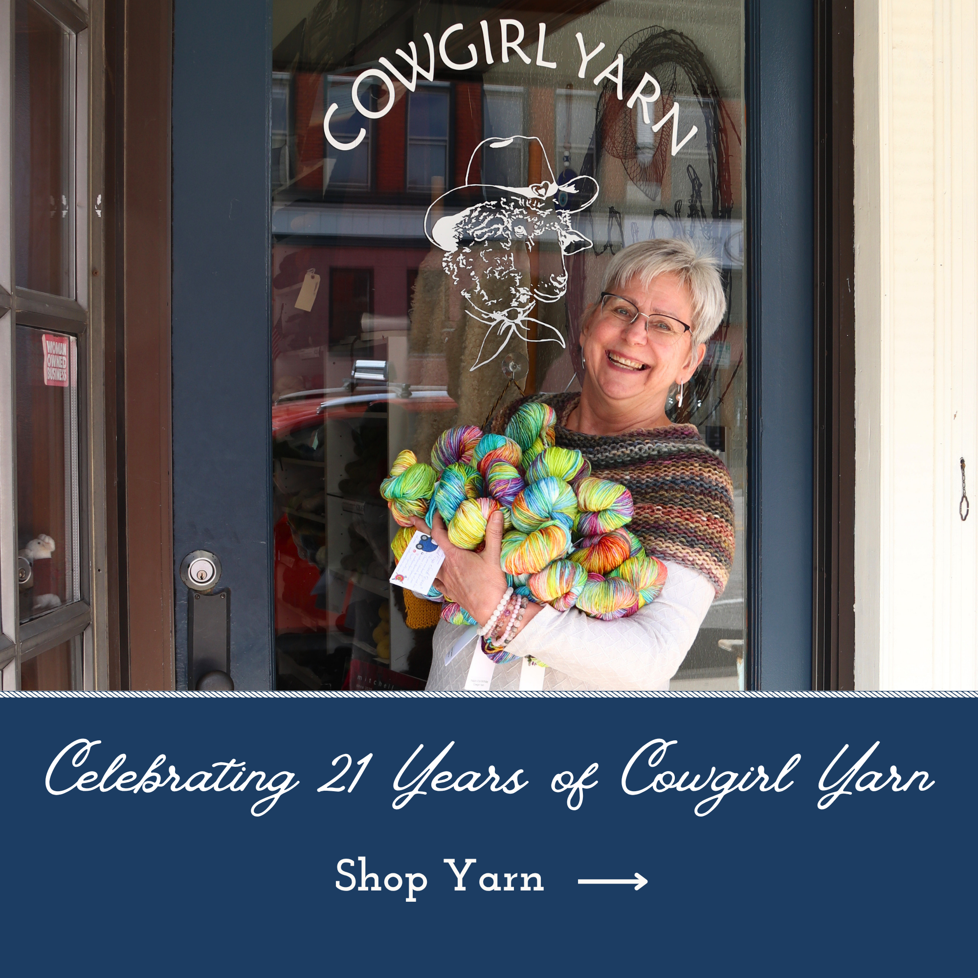 Lori at the front door of cowgirl yarn smiling and holding yarn