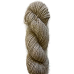 A single twisted skein of soft, fuzzy yarn in a light oatmeal beige color, photographed on a plain white background.