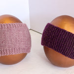 Two knitted headbands displayed on brown egg-shaped mannequins against a white background. The left headband is a dusty mauve-pink color, and the right headband is a deep purple.