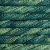 Close-up of twisted yarn skeins in a variegated blend of deep teal, forest green, and soft sage green.