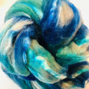 a braid of ready to be spun fiber color beige, teal, blue
