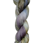 A skein of hand-dyed fingering/sock yarn color white grey tan blue purple black speckles