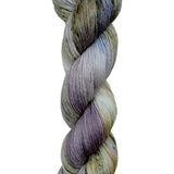 A skein of hand-dyed fingering/sock yarn color white grey tan blue purple black speckles