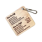 A square wooden keychain plaque with engraved instructions on how to do a make 1 left and make 1 right knit stitch, attached to a metal ball chain