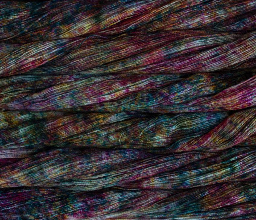 close up view of malabrigo silkpaca lace weight yarn color red teal yellow purple speckles
