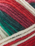 Close up of a skein of Deluxe Stripes in colorway 310 Poinsettia 