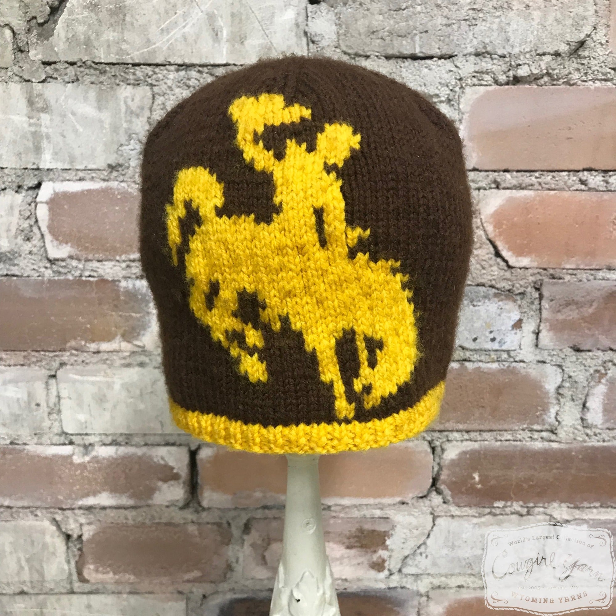 A brown and gold knitted beanie featuring the Steamboat symbol
