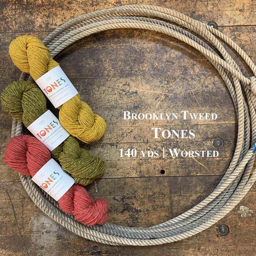 Three colorful hanks of Brooklyn Tweed Tones in a lasso on a wooden surface