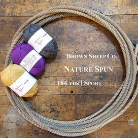 Balls of Brown Sheep Nature Spun Sport Yarn on a wooden surface