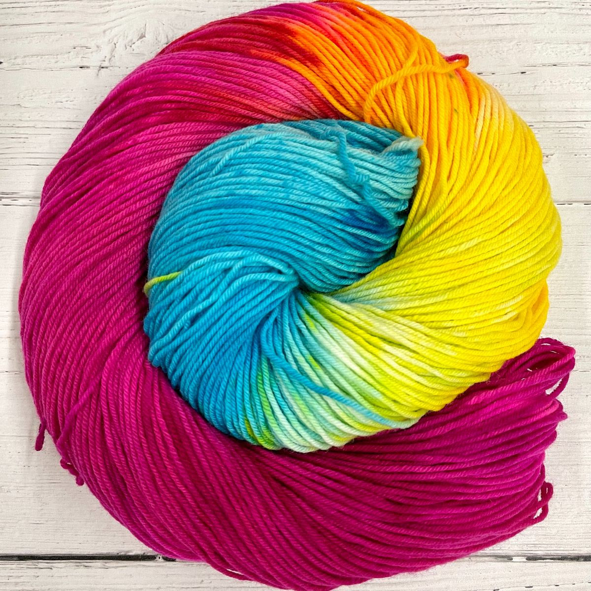 Knitted Wit Herstory 2022 yarn color Thirsty Thursday, a bright pink, blue and yellow skein