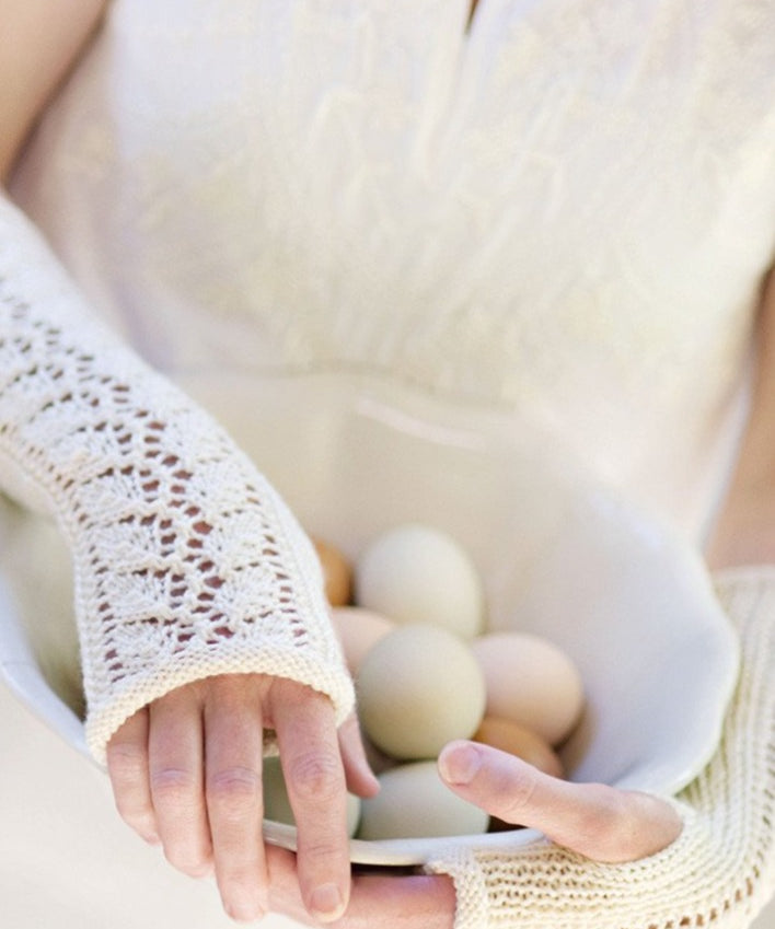 Woman wearing fingerless mitts holding eggs