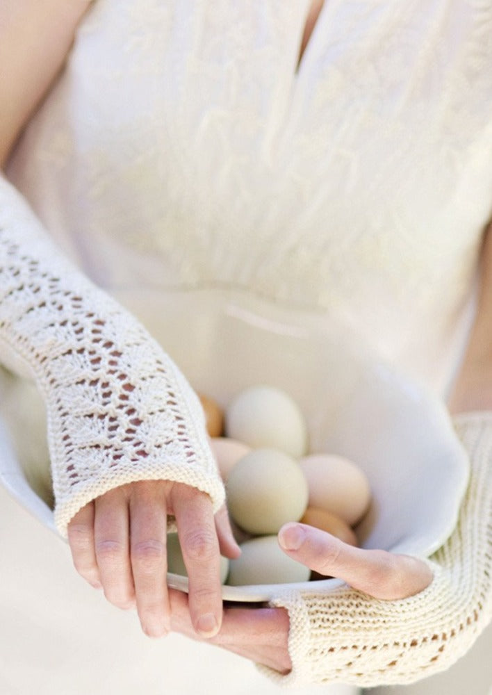 Woman wearing fingerless mitts holding eggs