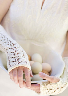 Woman wearing fingerless mitts holding eggs