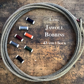 Seven Lang Jawoll Bobbins of various colors inside a lasso on a wooden table